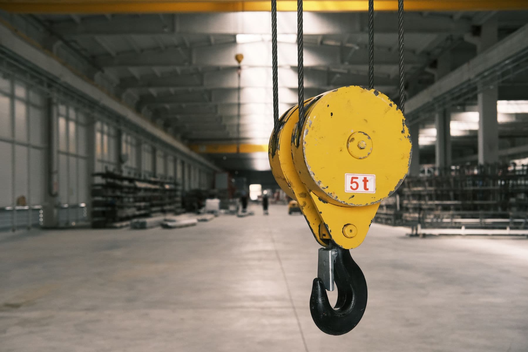 Closeup of a 5-ton yellow crane hook in an empty warehouse in Konya, Türkiye.