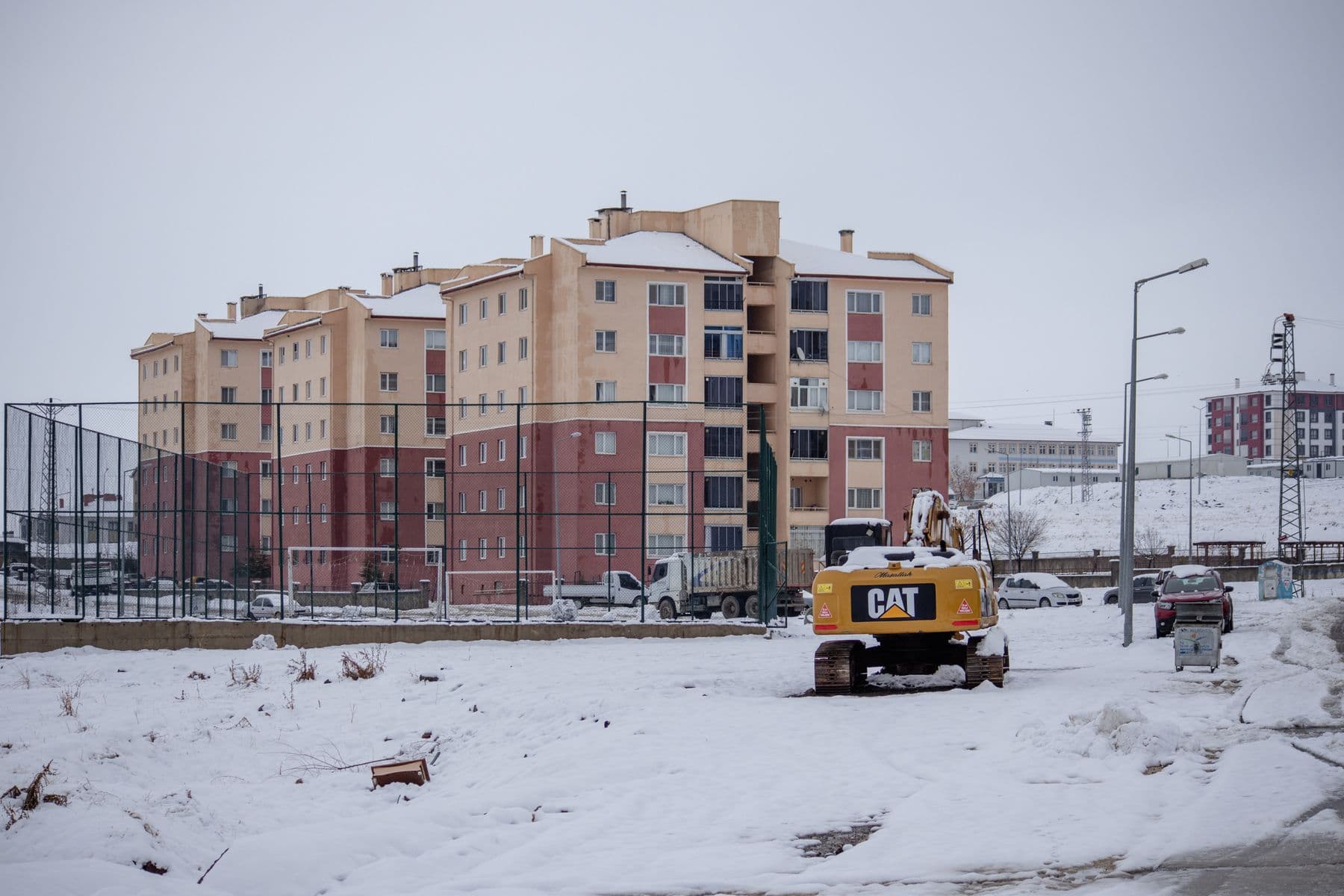 Snow-covered construction site and residential buildings in Palu, Türkiye, showcasing winter urban life.